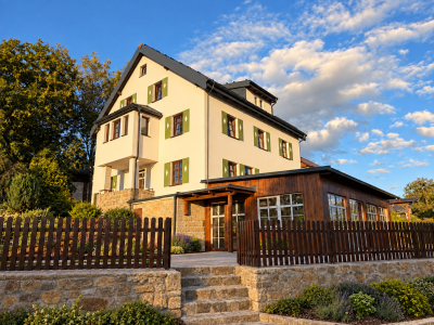 Visualization of renovated Building A at Resort Mezná, featuring a restaurant, wooden facade, natural stone details and green shutters.